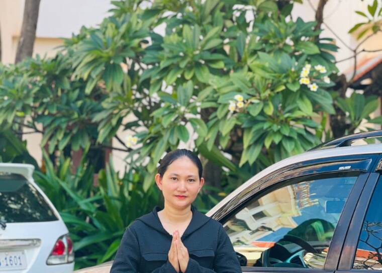 A woman driver greeting her guest beside a car